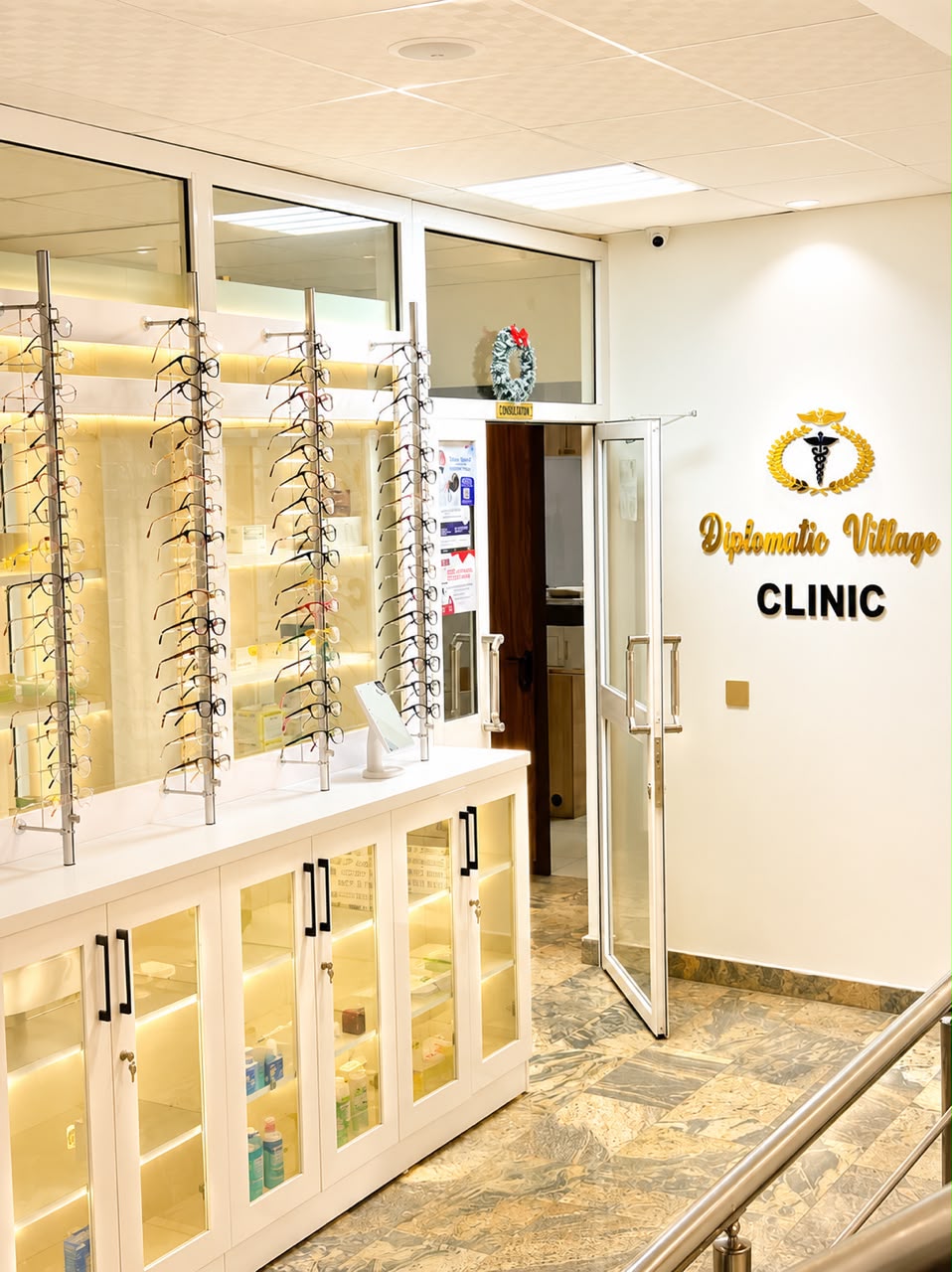 Entrance to Diplomatic Village Clinic, with the clinic signage beside the optical dispensary