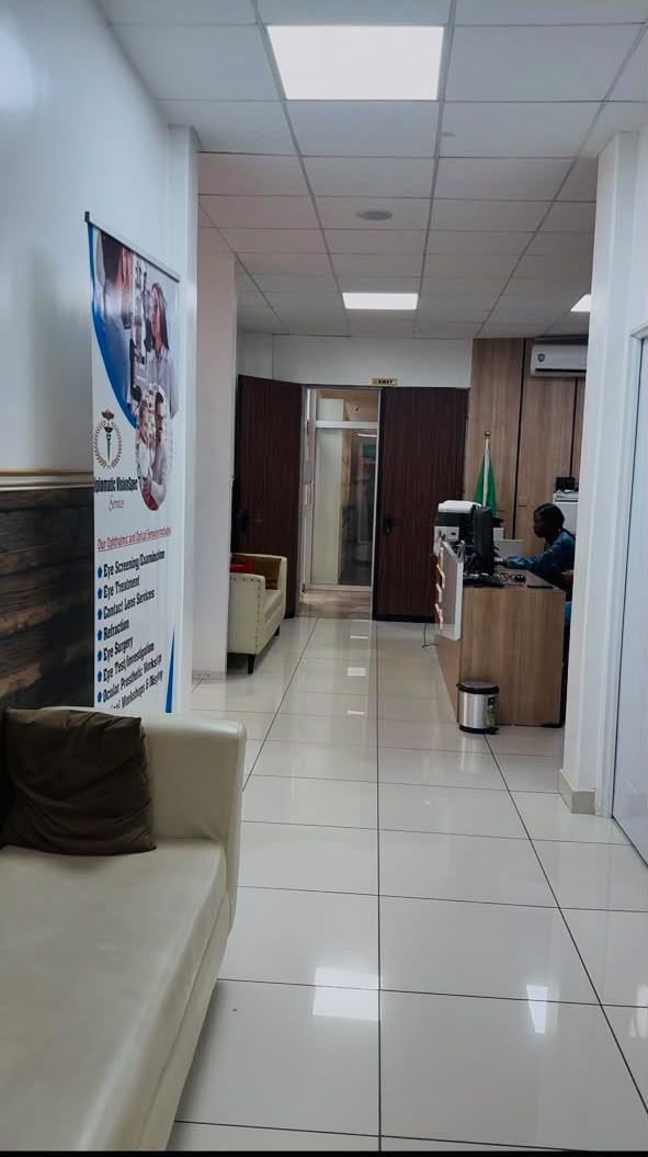 Clinic team member at the desk beside a board listing Diplomatic Village Clinic's screening and investigation services