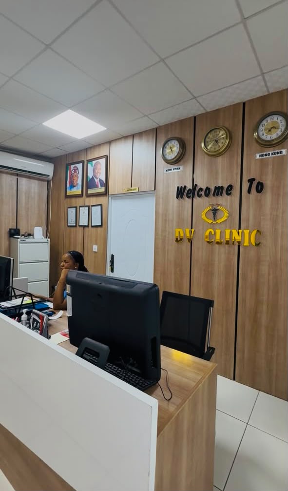 Front desk at Diplomatic Village Clinic beneath the "Welcome to DV Clinic" wall